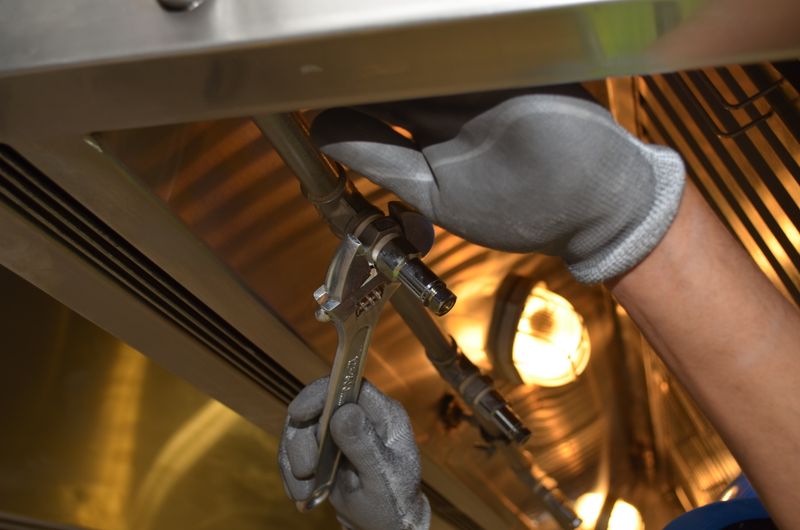 Plumber's gloved hands with wrench under a sink